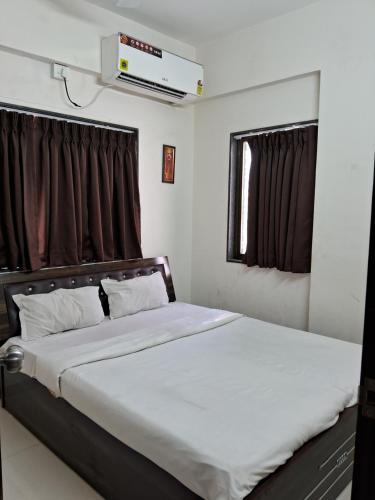 a bedroom with a bed with white sheets and a window at Paradise inn in Alandi