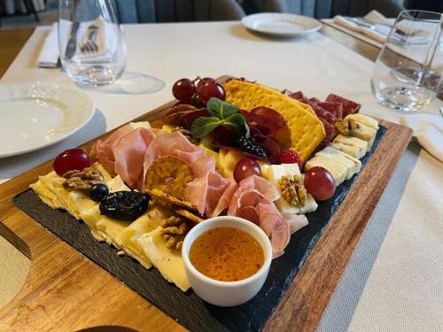 a tray of meats and cheese and a dipping sauce at Hotel Brilliant Plaza in Zalău