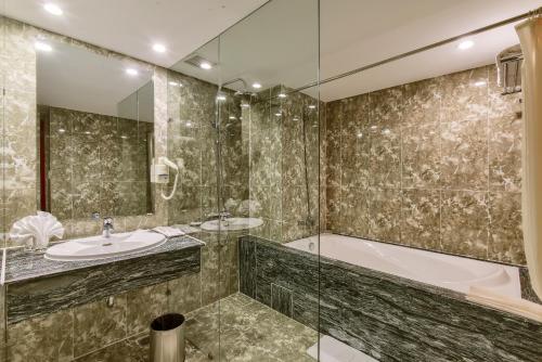 y baño con bañera, lavamanos y ducha. en Khách sạn Park Hotel Dalat, en Da Lat