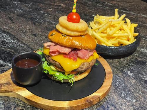 a plate with a hamburger and fries and a cup of ketchup at Hotel Brilliant Plaza in Zalău