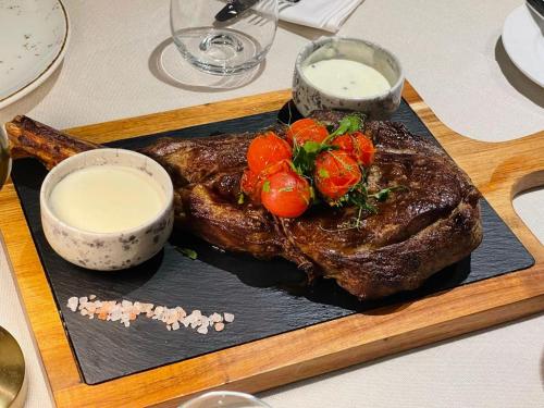 a plate of steak with tomatoes and sauce on a table at Hotel Brilliant Plaza in Zalău