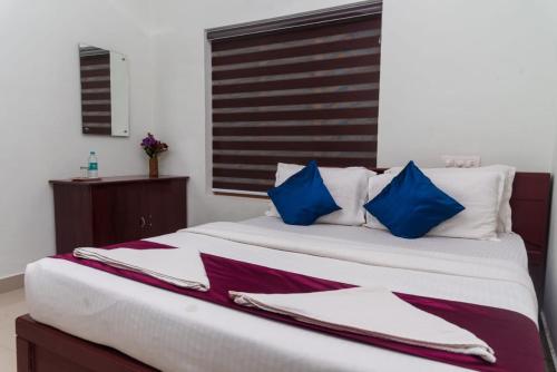 sypialnia z dużym łóżkiem z niebiesko-białymi poduszkami w obiekcie pookode villa w mieście Vythiri