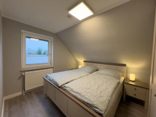 a bedroom with a bed and a window at Windfang 2 in Hooksiel in Wangerland