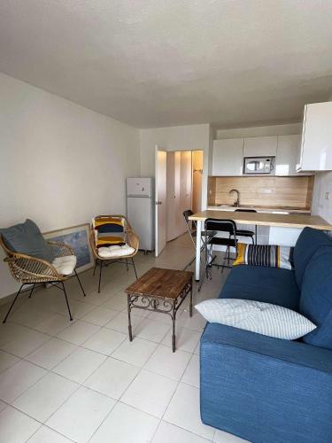 un salon avec un canapé bleu et une cuisine dans l'établissement Ref 564 Seignosse océan, bel appartement VUE MER , proche plage et centre, 4 personnes, à Seignosse