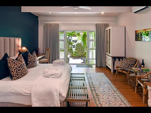 a bedroom with two beds and a table and chairs at Ashbourne Boutique Guest House in Franschhoek