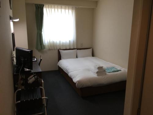 a small bedroom with a bed and a window at Hotel Green Palace in Sendai
