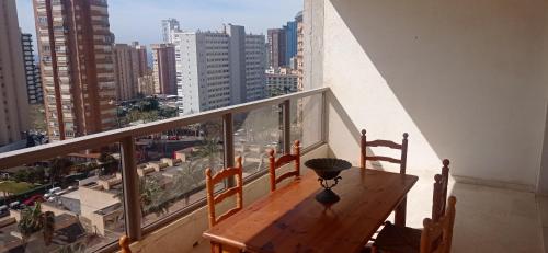 a balcony with a wooden table and chairs and a city at Apartamet Benidorm in Benidorm