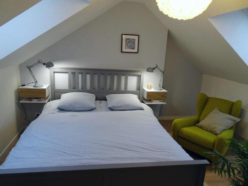 Un dormitorio con una cama y una silla verde. en Gîte en plein coeur du vignoble chablisien, en Courgis