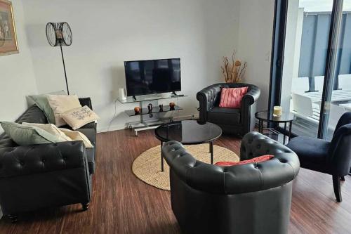 a living room with leather furniture and a flat screen tv at ARSAV Vue Mer et Plage in Port-Louis