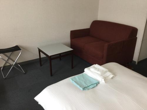 a room with a bed with a chair and a couch at Hotel Green Palace in Sendai