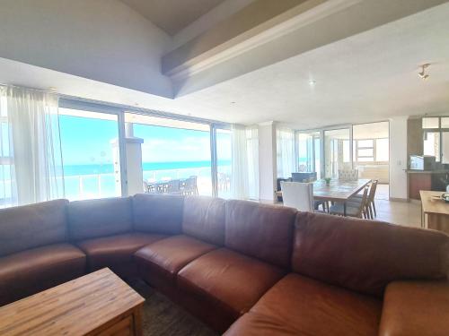 a living room with a brown couch and a table at Santorini A-Block Penthouse in Margate
