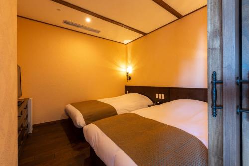 two beds in a room with yellow walls at La Vista Kirishima Hills in Kirishima
