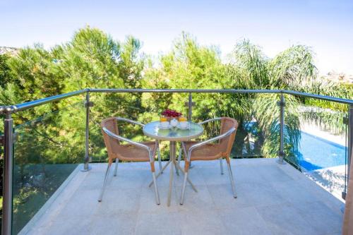 a glass table and two chairs on a balcony at Lucile - Coralli Beachfront Apartment in Paralimni