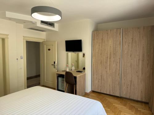 Schlafzimmer mit einem Bett, einem Schreibtisch und einem TV in der Unterkunft Mervin Hotel in Kruja