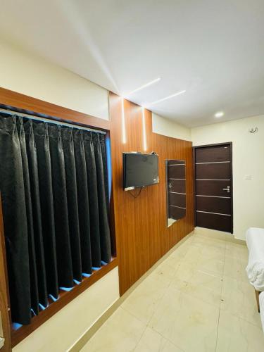 a room with a tv and some black curtains at Royal Plaza City in Kozhikode