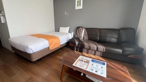 鹿児島市にあるアパートメントホテル イコットのベッドと革張りのソファが備わる客室です。