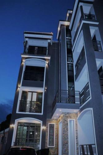 a tall white building with a lot of windows at Alo's Apartment_KISASI in Kampala