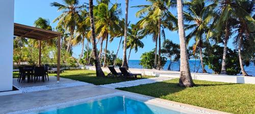 a resort with a swimming pool and palm trees at Villa Shepherd Zanzibar - LUXURY BEACH FRONT - KIWENGWA in Kumba Urembo