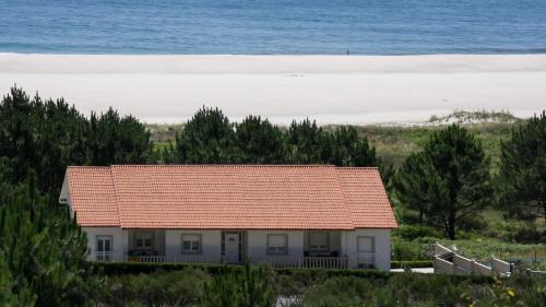une maison avec un toit rouge en face de la plage dans l'établissement Agro Hermida 4, à Gándara