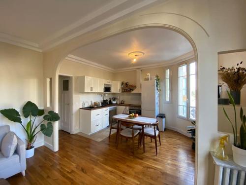 Appartement de charme Quartier des Batignolles في كليشي: مطبخ وغرفة معيشة مع طاولة وكراسي
