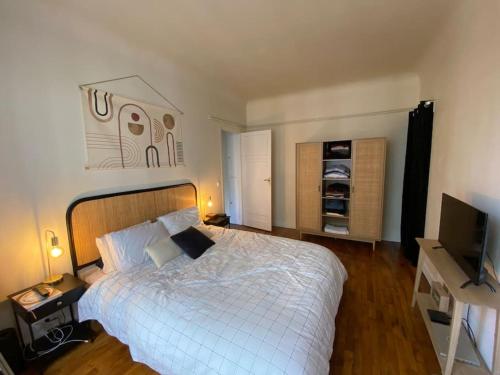 Appartement de charme Quartier des Batignolles في كليشي: غرفة نوم بسرير ابيض وتلفزيون