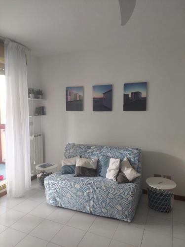 a blue couch in a white room with pictures on the wall at Monolocale La Conchiglia in Sestri Levante