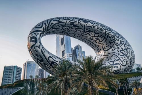 a large metal sculpture in front of a city at Novotel Dubai Gold District in Dubai