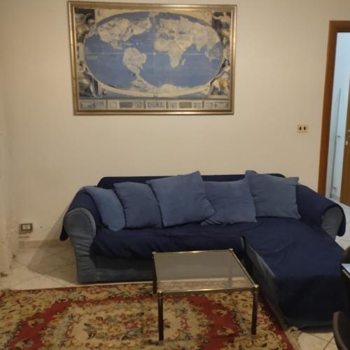 un divano blu in soggiorno con una mappa sul muro di Affittagemma ad Asti