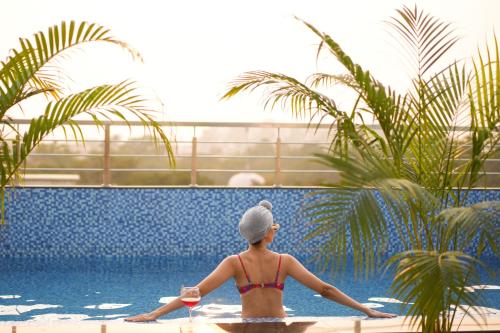 a woman in a bikini sitting next to a swimming pool at The LIV Hotel Jaipur in Jaipur