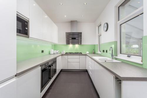 une grande cuisine avec des placards blancs et des murs verts dans l'établissement Castlehill Road, à Ayr