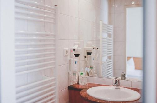 a white bathroom with a sink and a mirror at Hotel Löwen-Seckenheim in Mannheim