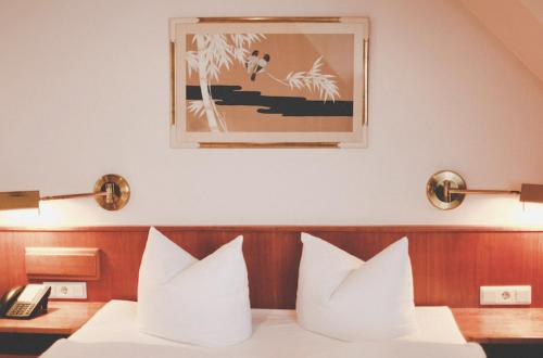 uma cama com almofadas brancas e uma fotografia na parede em Hotel Löwen-Seckenheim em Mannheim