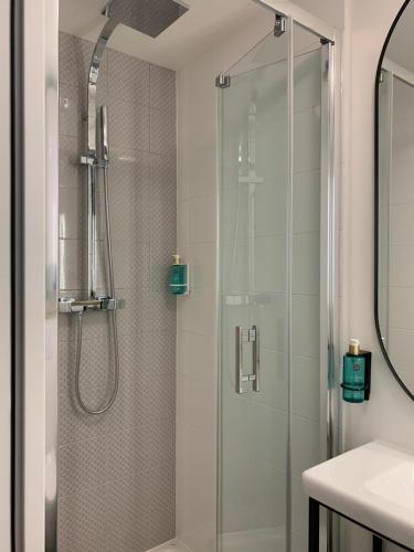 a shower with a glass door in a bathroom at Appart Hôtel Victoria in Vincennes