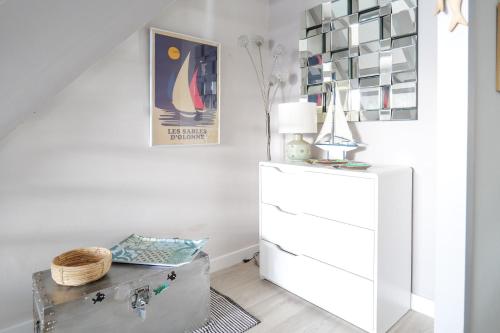 une chambre blanche avec une commode et une lampe dans l'établissement Maison dans résidence proche océan Les Sables - 4 pers, à Saint-Hilaire-de-Talmont