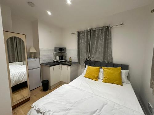 1 dormitorio con 1 cama blanca grande con almohadas amarillas en 2nd Studio Flat With Great Views in Keedonwood Road With Private Kitchenette and shared bathroom en Bromley