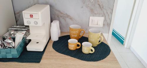 a coffee maker and four coffee mugs on a table at Il bacio del sole in Campomarino