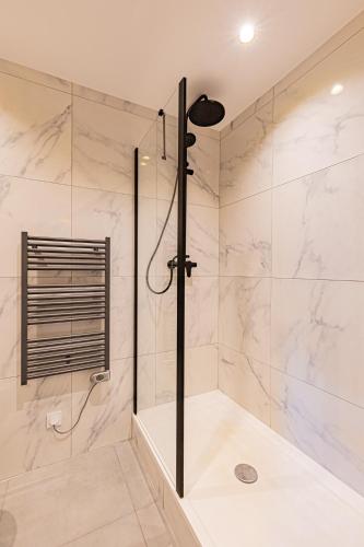 une salle de bain avec une douche avec une porte vitrée dans l'établissement Le p’tit Jacques - C La Chouette, à Dijon