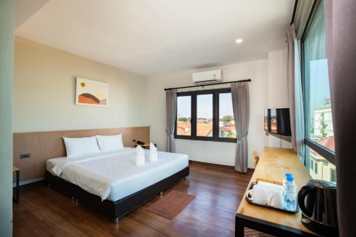 a bedroom with a large white bed and a window at Siri Hotel in Vientiane