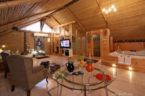 a living room with a glass table and a couch at ביקתפוז וקלמנטינה- מתחם בקתות וסוויטות עם ג'קוזי פרטי ובריכה משותפת in Liman