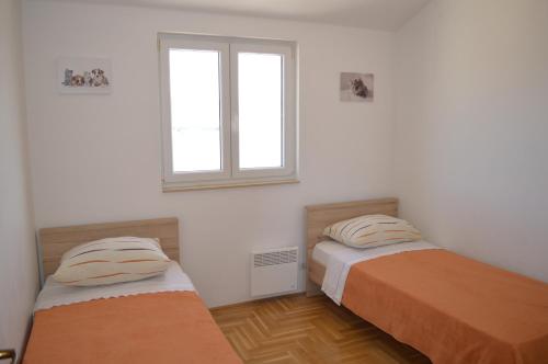 two beds in a room with a window at Apartment Quattro in Trogir