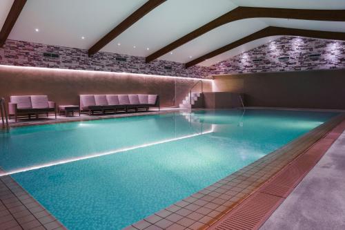 uma grande piscina num hotel com cadeiras roxas em Ashdown Park Hotel em Forest Row