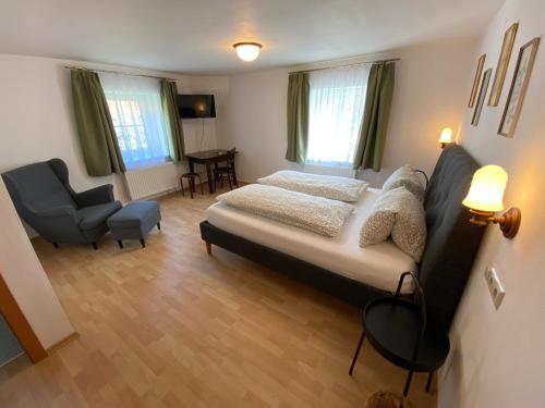 a bedroom with a bed and a chair at Frühstückspension Haus Ebersdorf in Leiben