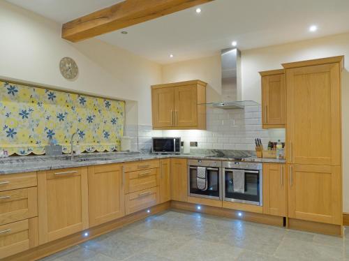 uma grande cozinha com armários e electrodomésticos de madeira em West Nymph Holiday Cottages Leafy Nook em South Tawton