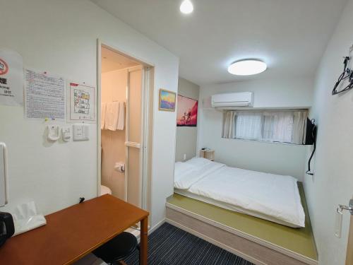 Cette petite chambre comprend un lit et un bureau. dans l'établissement da inn, à Osaka