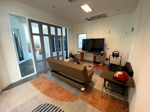 Centerpoint Koh Phangan New في تونغسالا: غرفة معيشة مع أريكة وتلفزيون بشاشة مسطحة