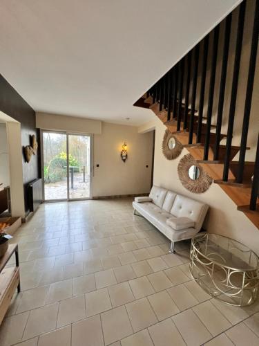 a living room with a couch and a staircase at La Lumineuse du Moulin in Saint-Germain-sur-Bresle