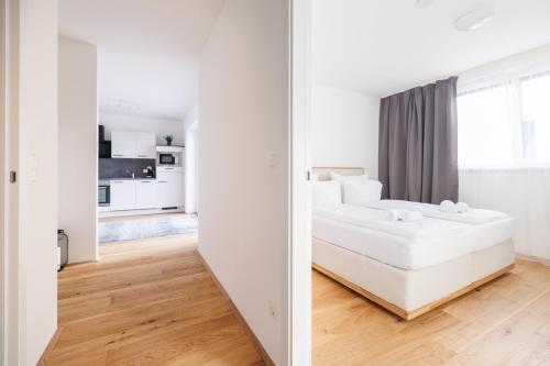 um quarto branco com uma cama e uma cozinha em SYMPHONY Apartments 42 - Modern Loft with Terrace and Grill in Central Location em Viena