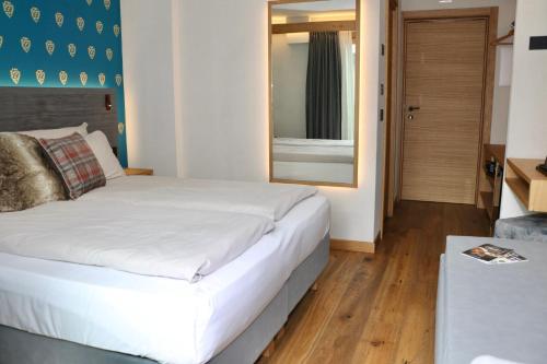a bedroom with a white bed and a mirror at Hotel Galli's - Centro in Livigno