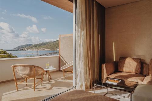 a bedroom with a balcony with a couch and a table at Aguas de Ibiza Grand Luxe Hotel - Small Luxury Hotel of the World in Santa Eularia des Riu