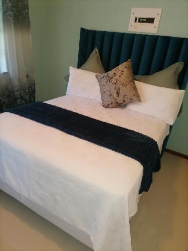 a large bed with white sheets and pillows at Busap in Port Shepstone